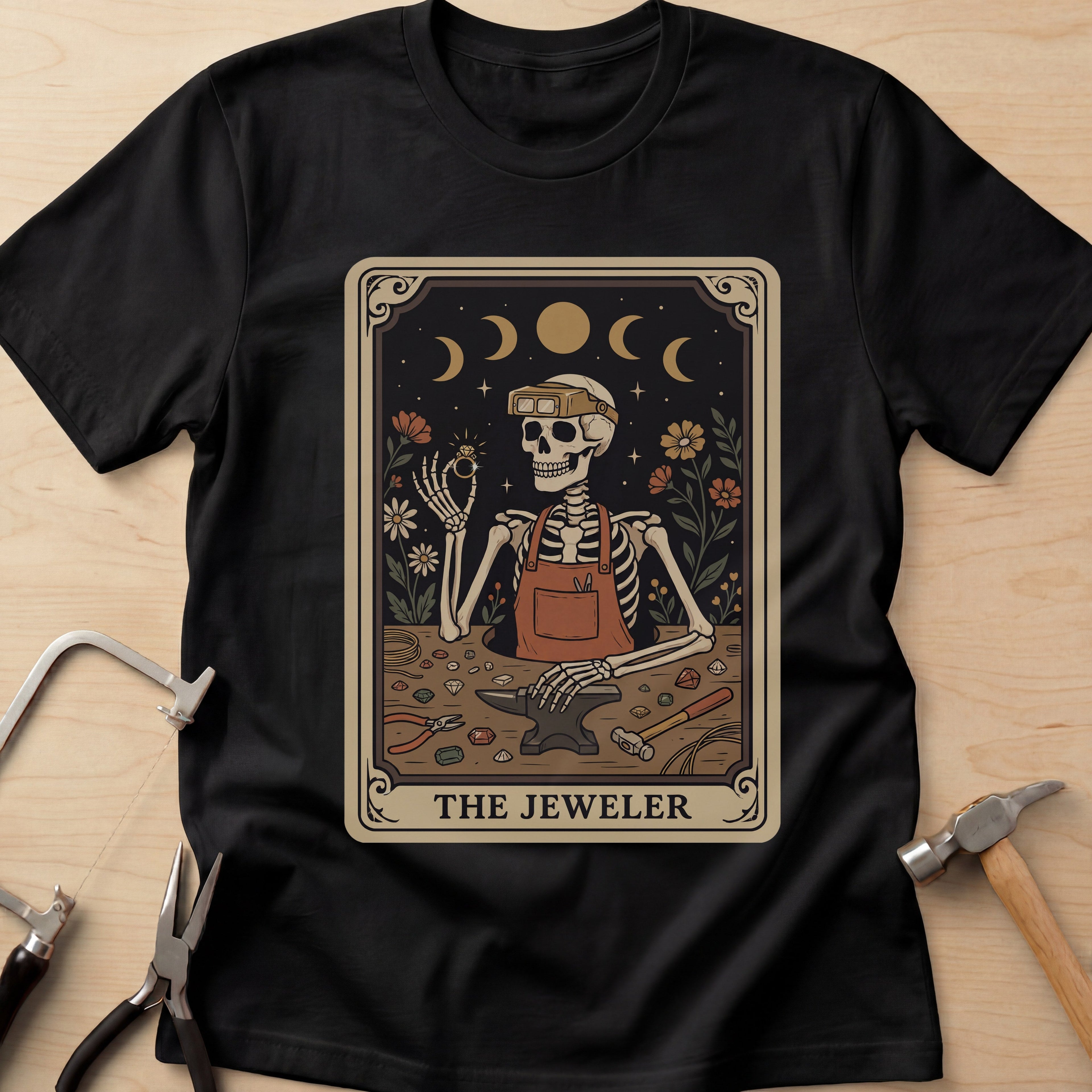 The Jeweler Tarot (Daisies) jewelry maker t-shirt in Black, flat lay with jeweler's tools
