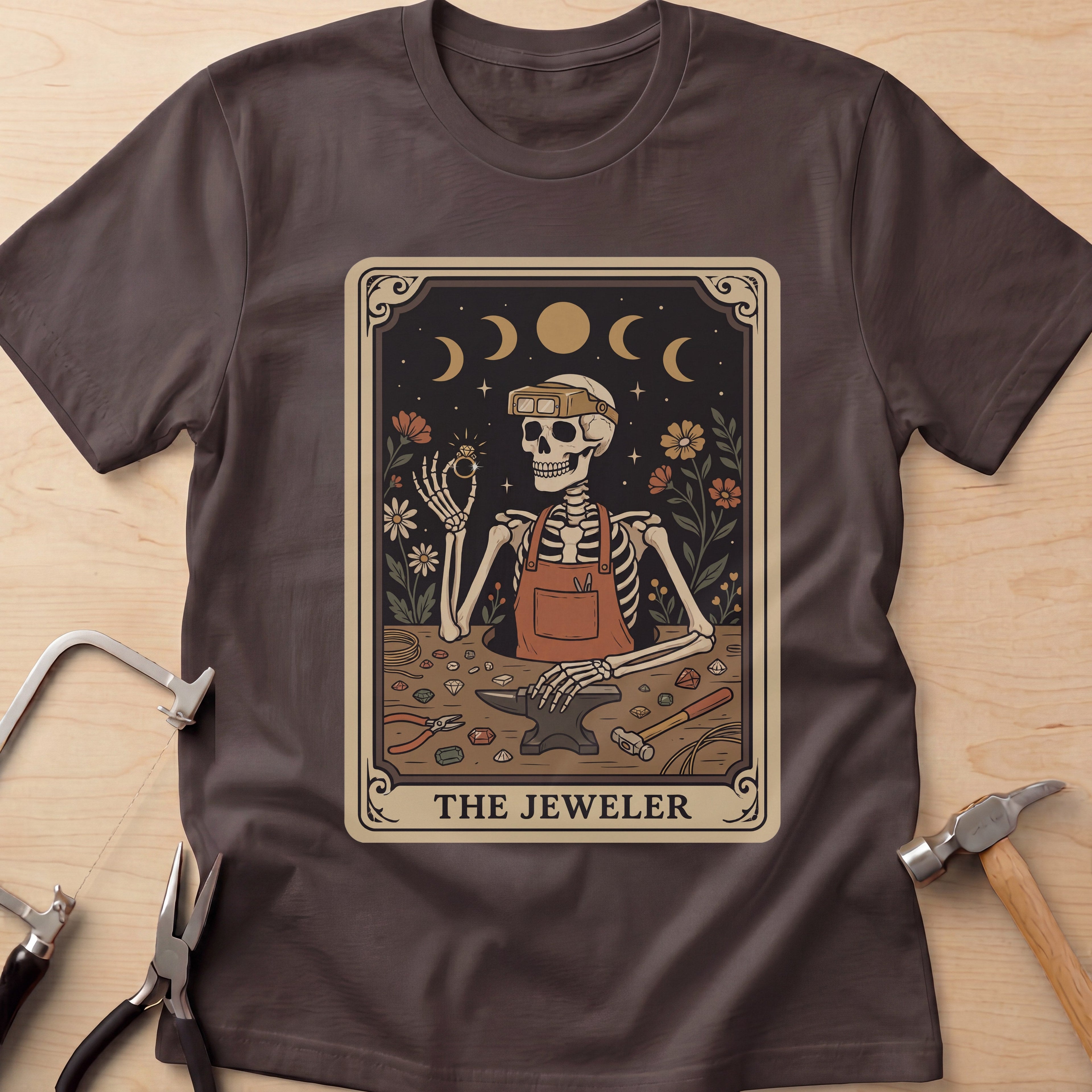The Jeweler Tarot (Daisies) jewelry maker t-shirt in Dark Chocolate, flat lay with jeweler's tools